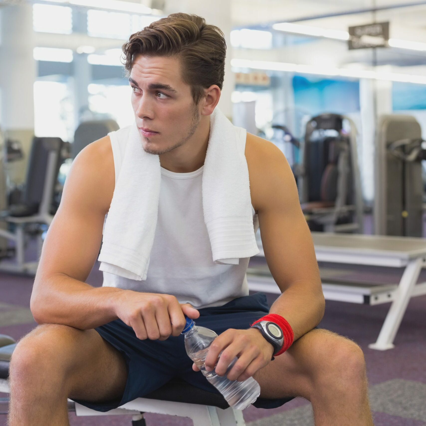 Fit man taking a break from working out at the gym